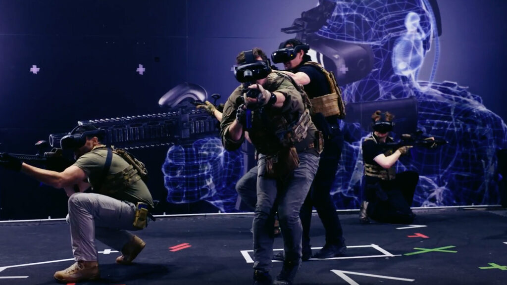 Image of 4 people dressed in military uniform with replica long arm rifles, wearing Operator XR VR kit, doing a training exercise.